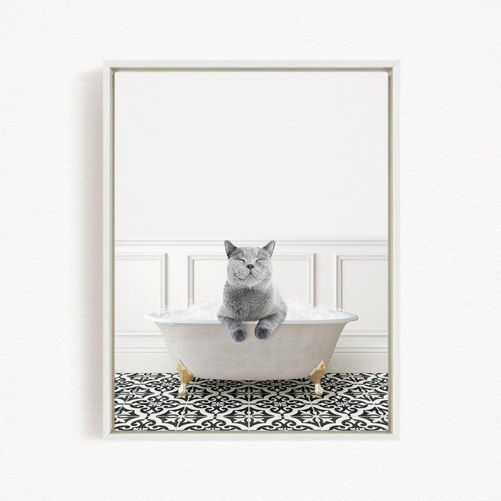A gray cat sitting in a white bathtub filled with bubbles, with a black and white patterned floor in the background.