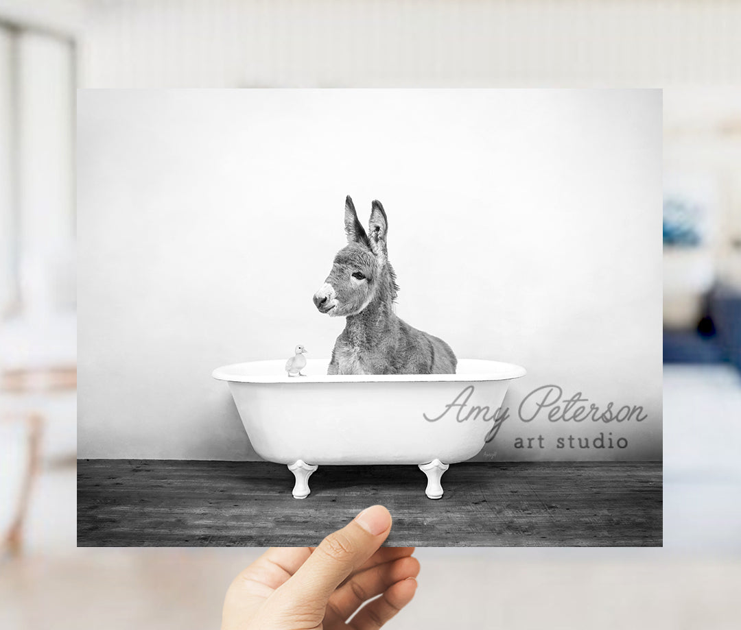 a person holding up a photo of a donkey in a bathtub