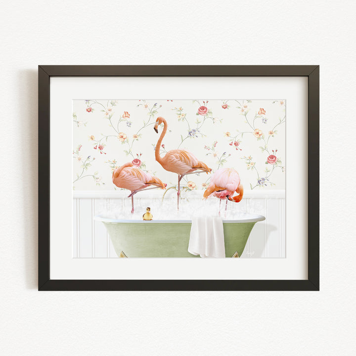 A framed image depicting three pink flamingos standing in a green bathtub filled with water, surrounded by a floral pattern.