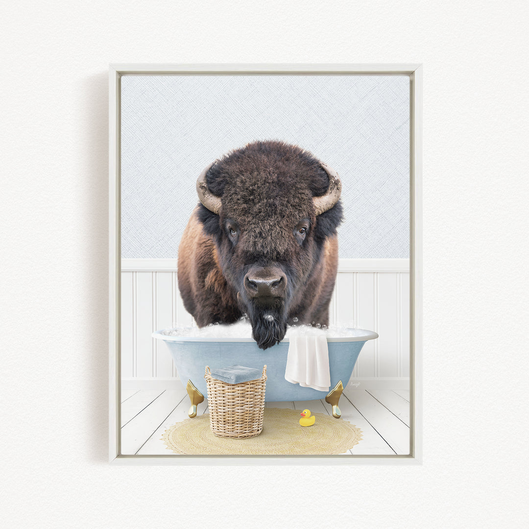 A buffalo with large horns is standing in a blue bathtub filled with water, surrounded by rubber ducks and a basket.