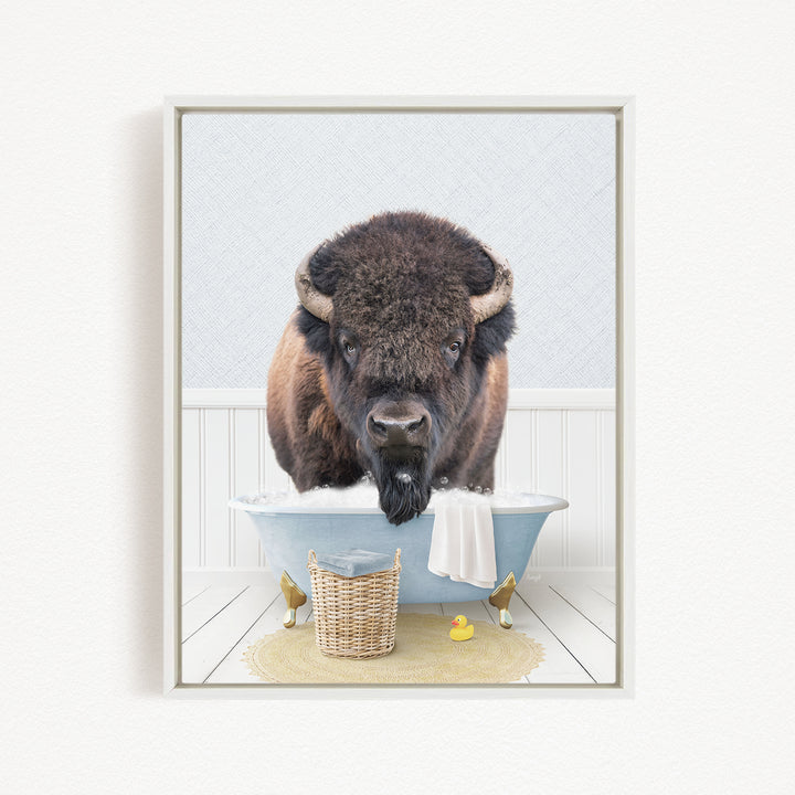 A buffalo with large horns is standing in a blue bathtub filled with water, surrounded by rubber ducks and a basket.
