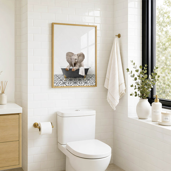 A bathroom with a white toilet, a framed picture of an elephant in a bathtub, and a window with greenery on the sill.