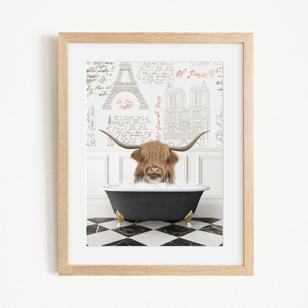 A framed image depicting a Highland cow sitting in a bathtub, with a Paris-themed background featuring the Eiffel Tower and other Parisian landmarks.