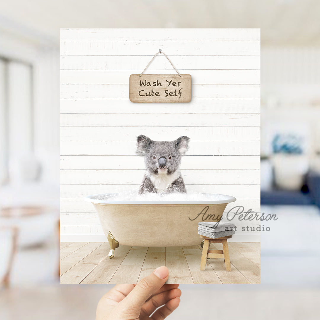 a hand holding a photo of a koala in a bathtub