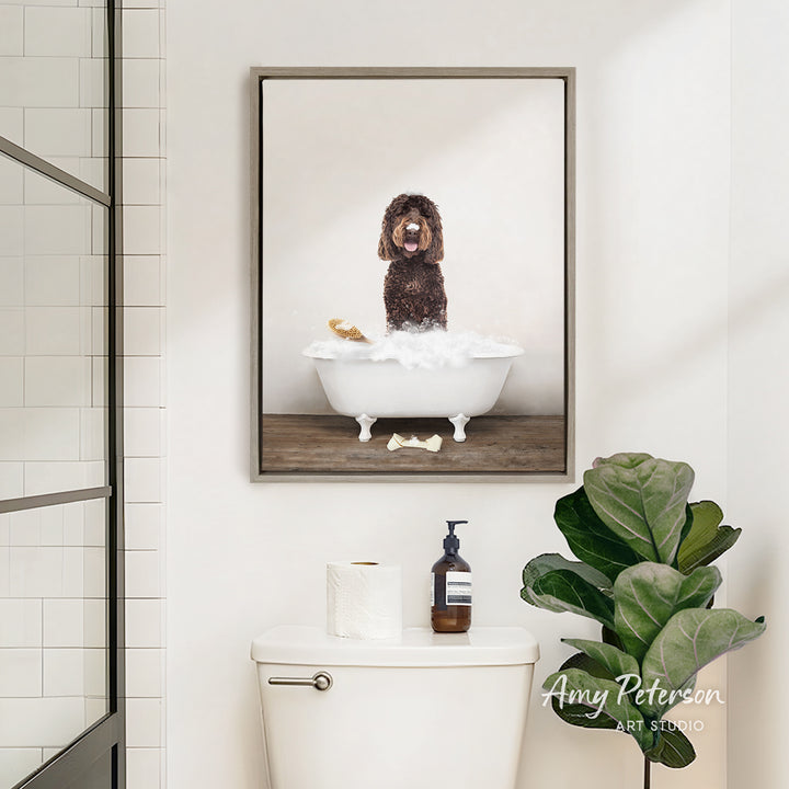 A framed image of a dog sitting in a bathtub, surrounded by bubbles, is displayed on the wall above a white toilet in a bathroom.