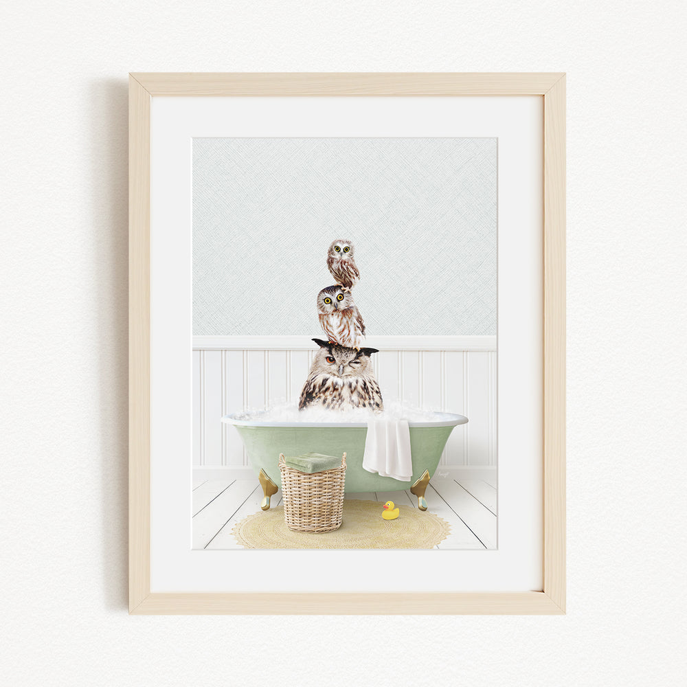 A framed image depicting a group of owls sitting on a green bathtub filled with water, with a yellow rubber duck floating nearby.
