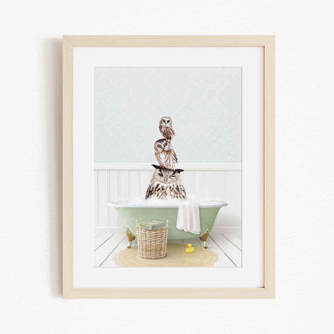 A framed image depicting a group of owls sitting on a green bathtub filled with water, with a yellow rubber duck floating nearby.