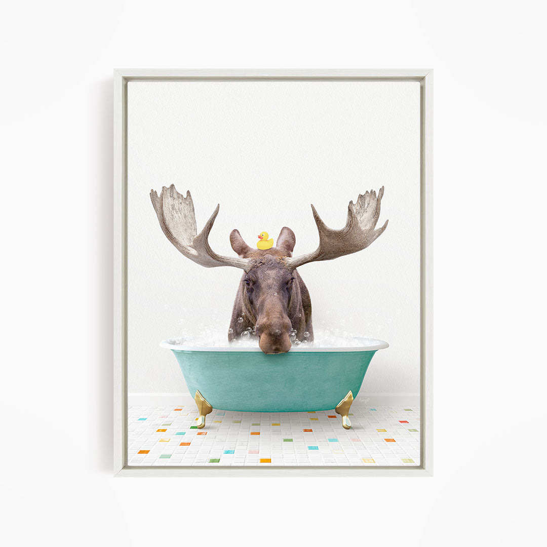 A moose with large antlers is sitting in a green bathtub, with a rubber duck floating on its head.