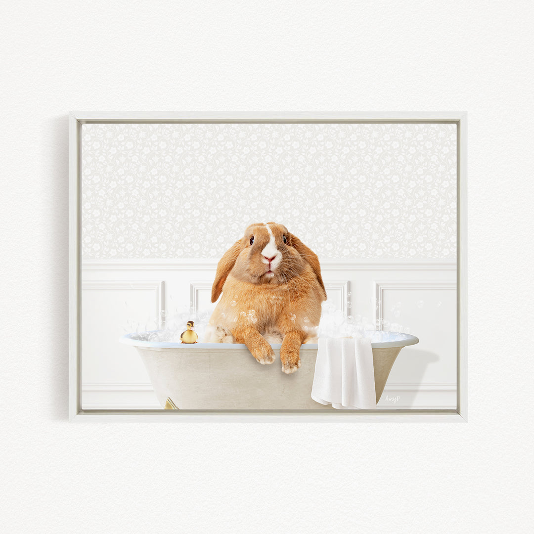 A brown rabbit sitting in a bathtub filled with water, surrounded by bubbles, with a towel and a small toy nearby.