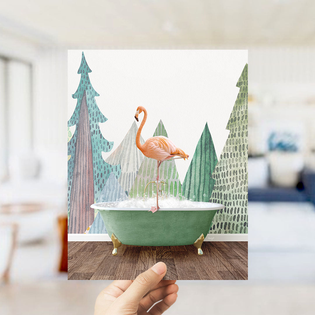 A hand holds up a framed image depicting a pink flamingo standing in a green bathtub, surrounded by a forest-themed background.