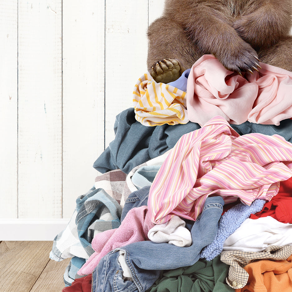 a brown bear sitting on top of a pile of clothes