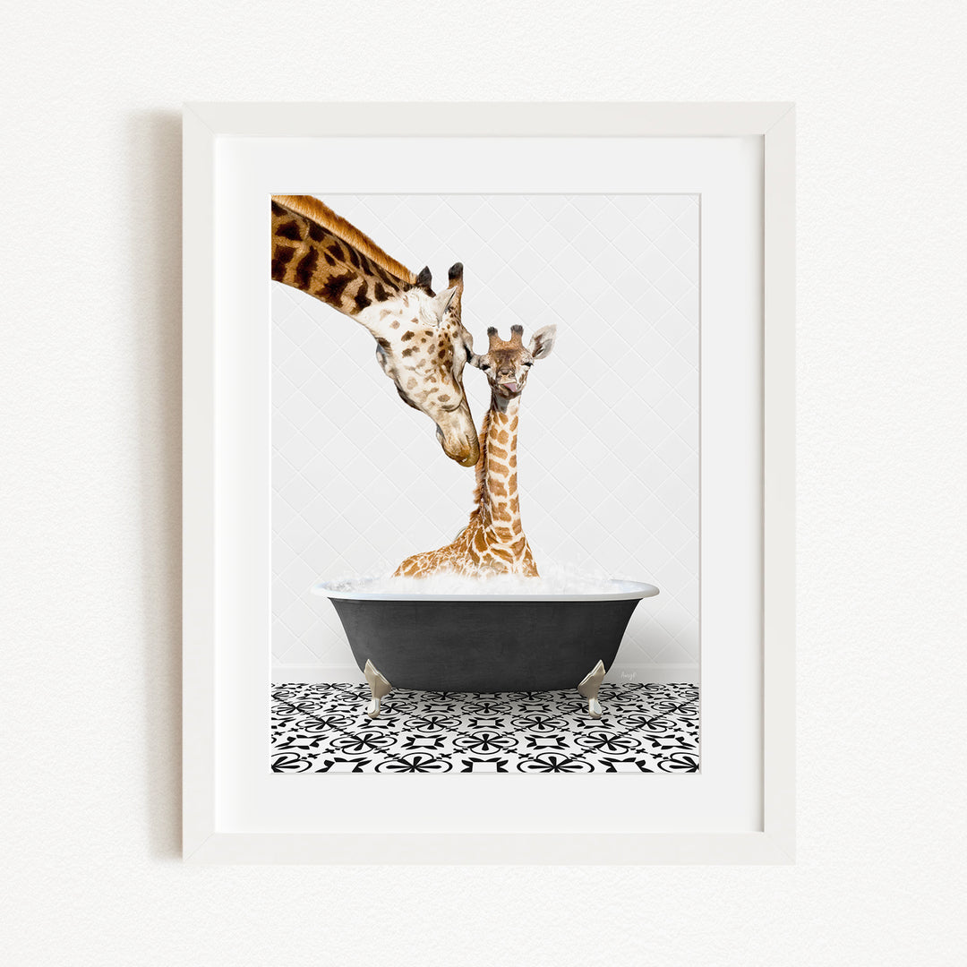 A mother giraffe and her baby giraffe are sitting together in a black bathtub, with the mother gently licking her baby.