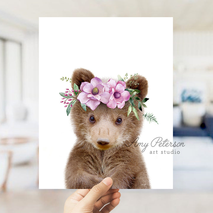 a hand holding a card with a picture of a teddy bear wearing a flower crown