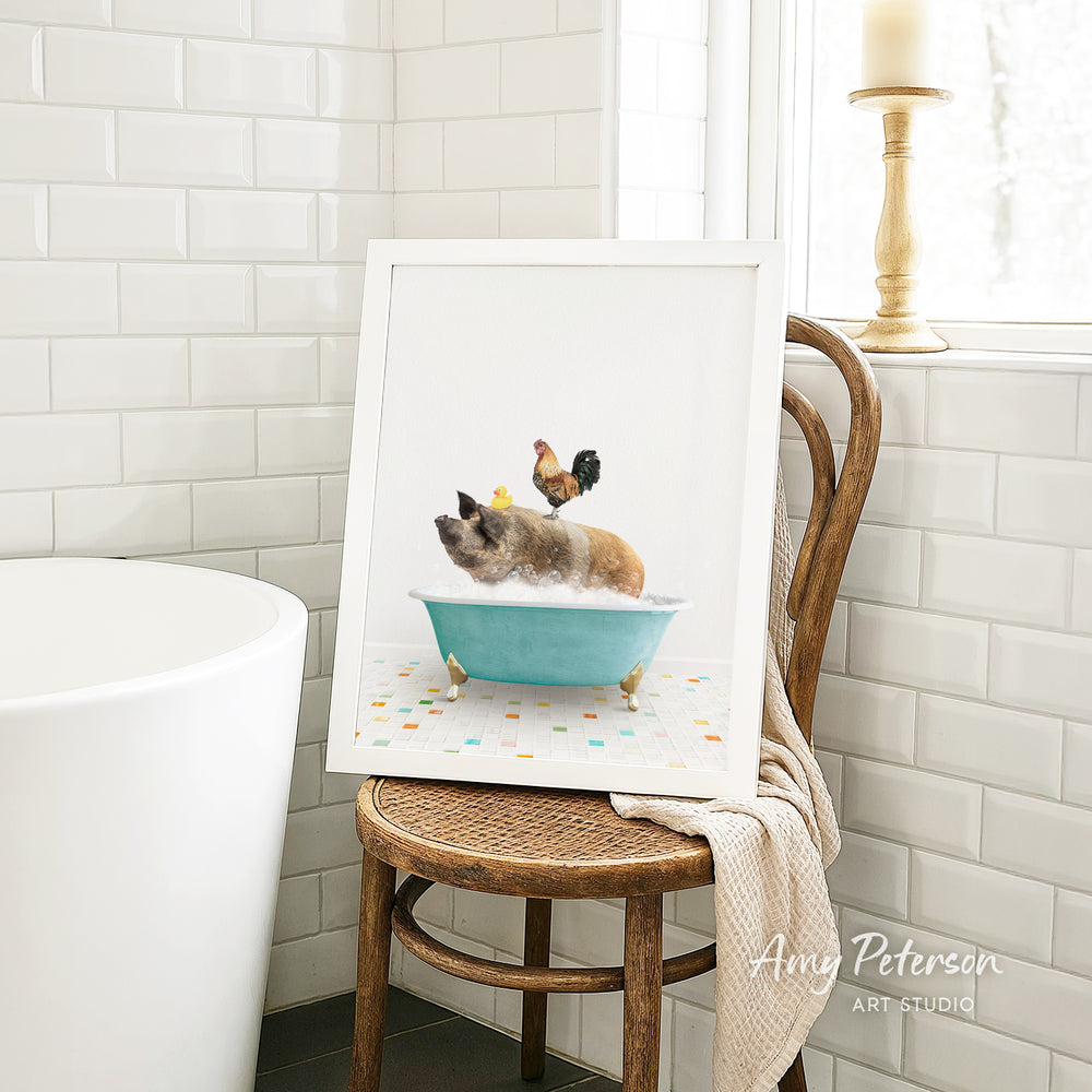 A framed image of a pig sitting in a blue bathtub, with a rooster perched on its back, is displayed on a wooden chair in a bathroom setting.