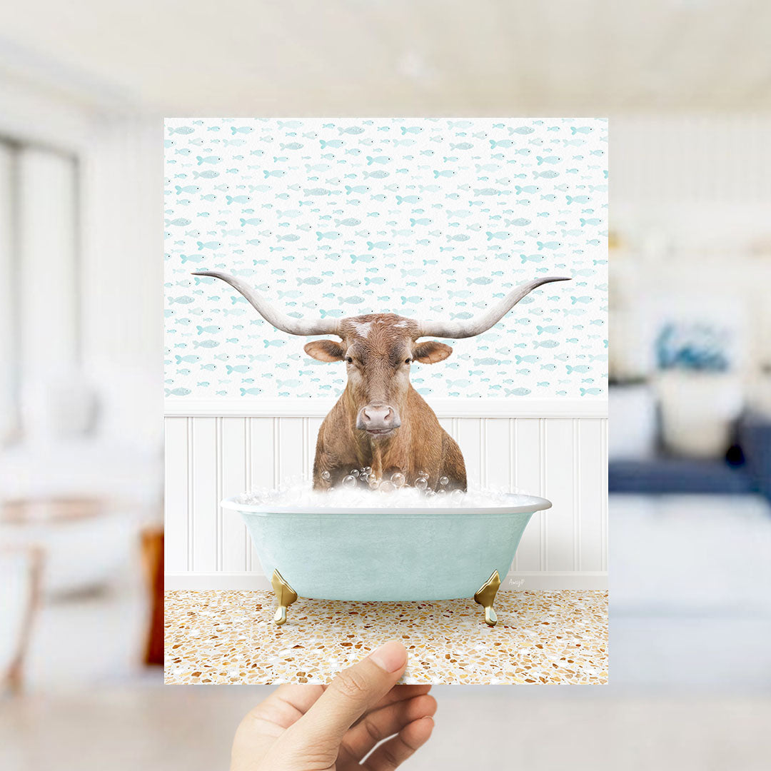 A brown bull with long horns is sitting in a light blue bathtub filled with bubbles, surrounded by a pattern of small fish.