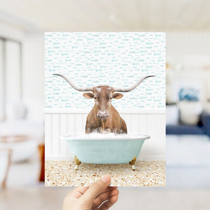 A brown bull with long horns is sitting in a light blue bathtub filled with bubbles, surrounded by a pattern of small fish.