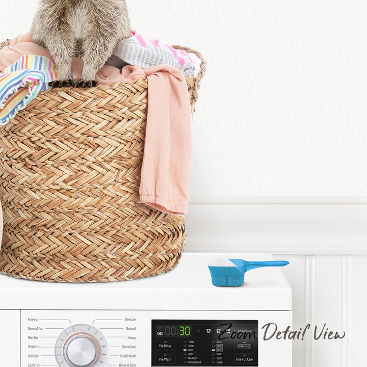 A laundry basket filled with clothes sits on top of a washing machine, with a small blue measuring cup placed on the front of the machine.