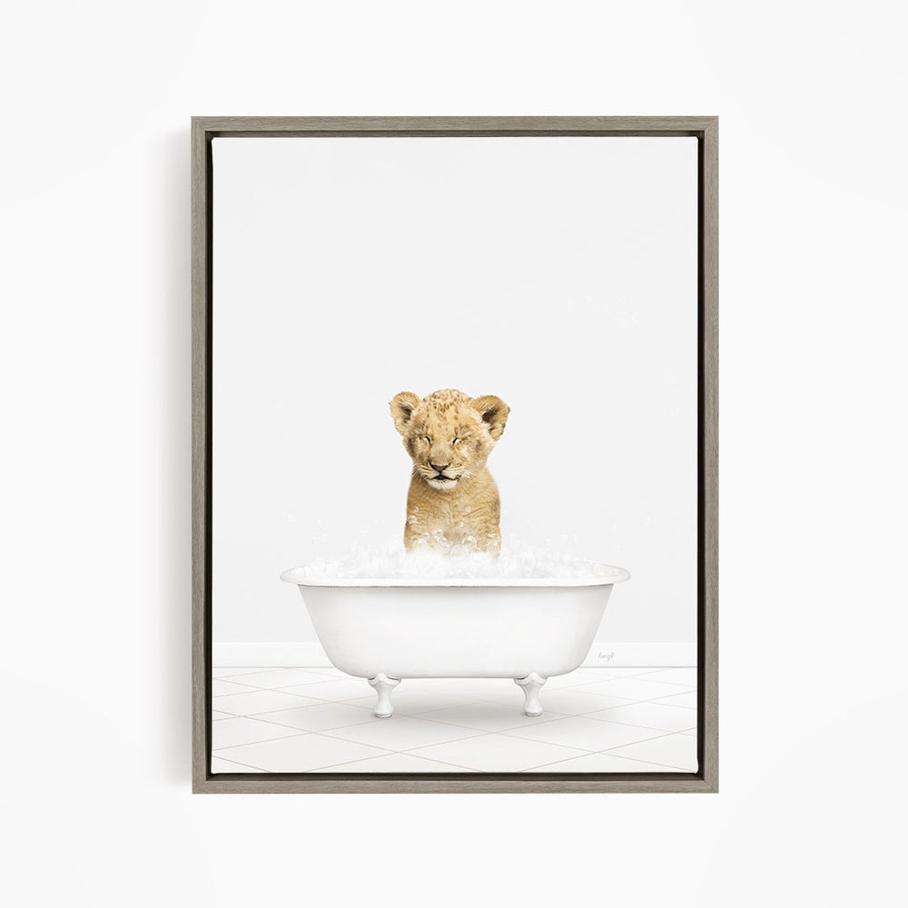 A young lion cub sitting in a white bathtub filled with water, looking up at the camera.