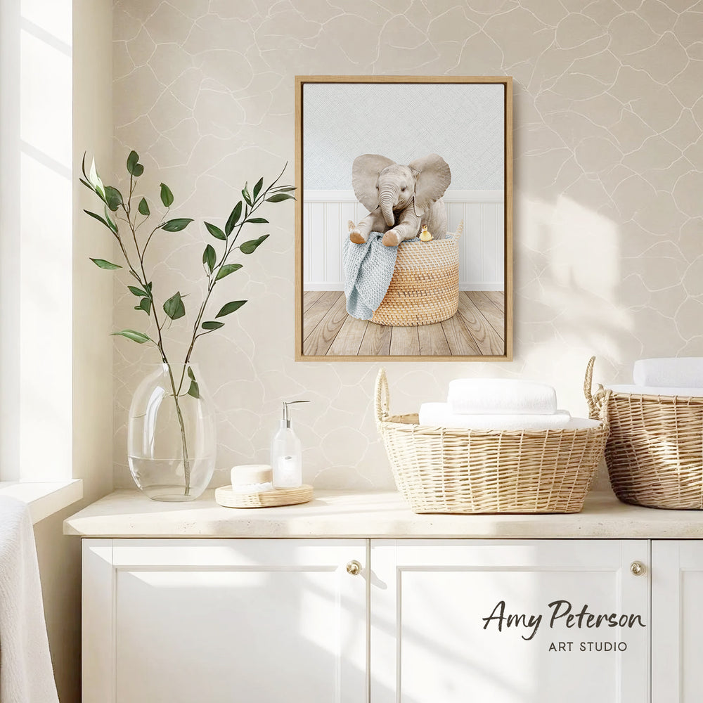 a framed photograph of two elephants sitting in a basket, placed on a wall above a white cabinet with baskets.