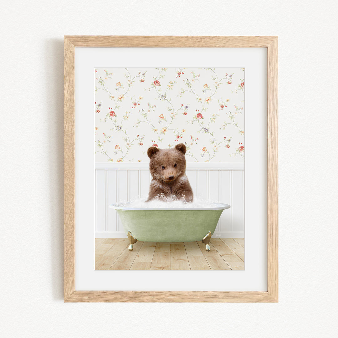 A cute brown bear sitting in a green bathtub filled with bubbles, set against a floral wallpaper background.