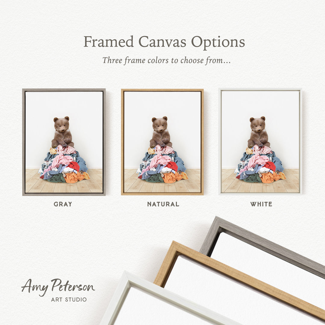 three framed canvas options, each featuring a teddy bear sitting on a pile of clothes. The options include a gray frame, a natural frame, and a white frame.