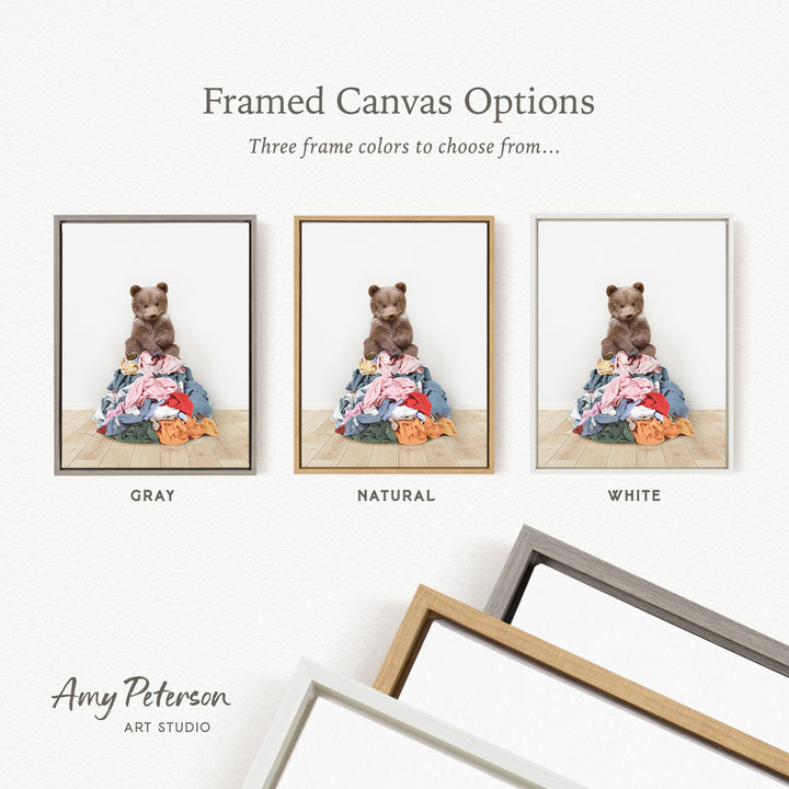 three framed canvas options, each featuring a teddy bear sitting on a pile of clothes. The options include a gray frame, a natural frame, and a white frame.