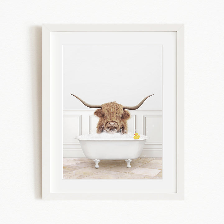 A Highland cow with large horns is sitting in a white bathtub, with a yellow rubber duck floating in the water.