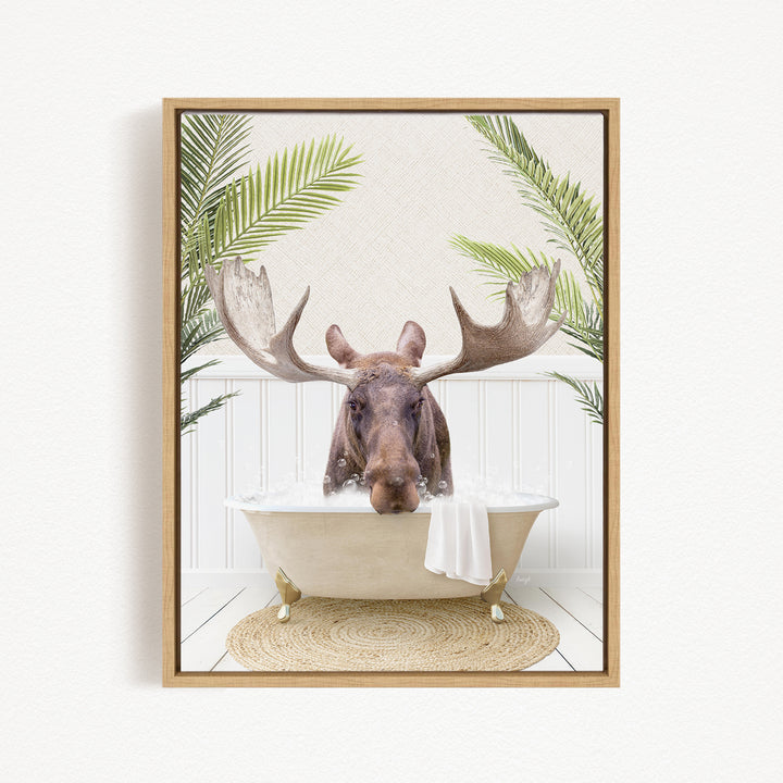 A moose with large antlers is sitting in a bathtub filled with water, surrounded by green leaves.