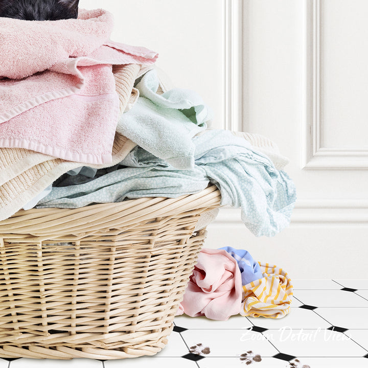 A wicker laundry basket filled with various folded clothes sits on a tiled floor.