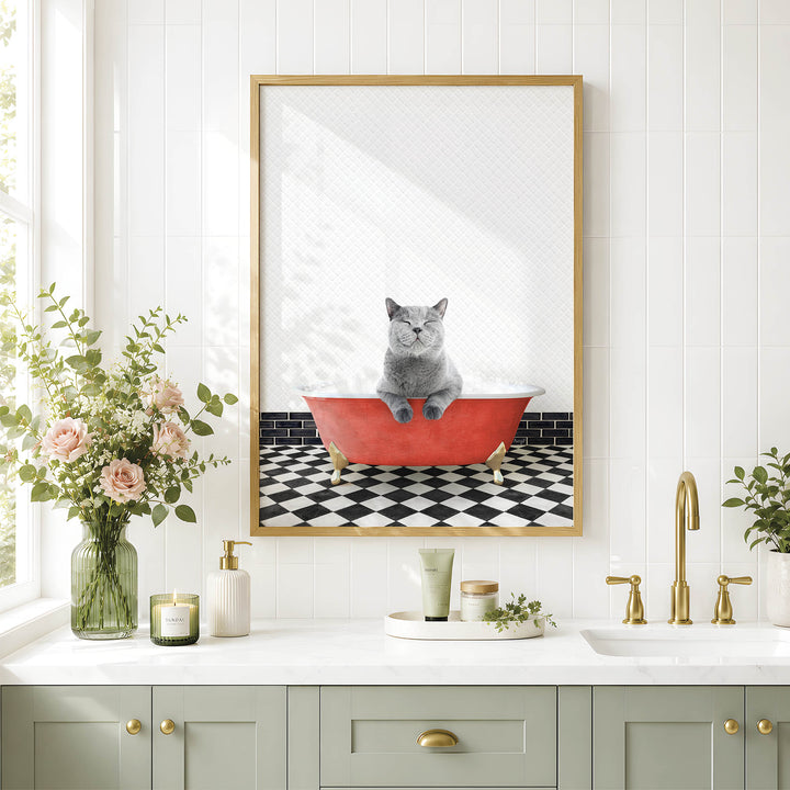 A framed image of a gray cat sitting in a red bathtub, surrounded by a black and white checkered floor, flowers, and a green vase on a white countertop.