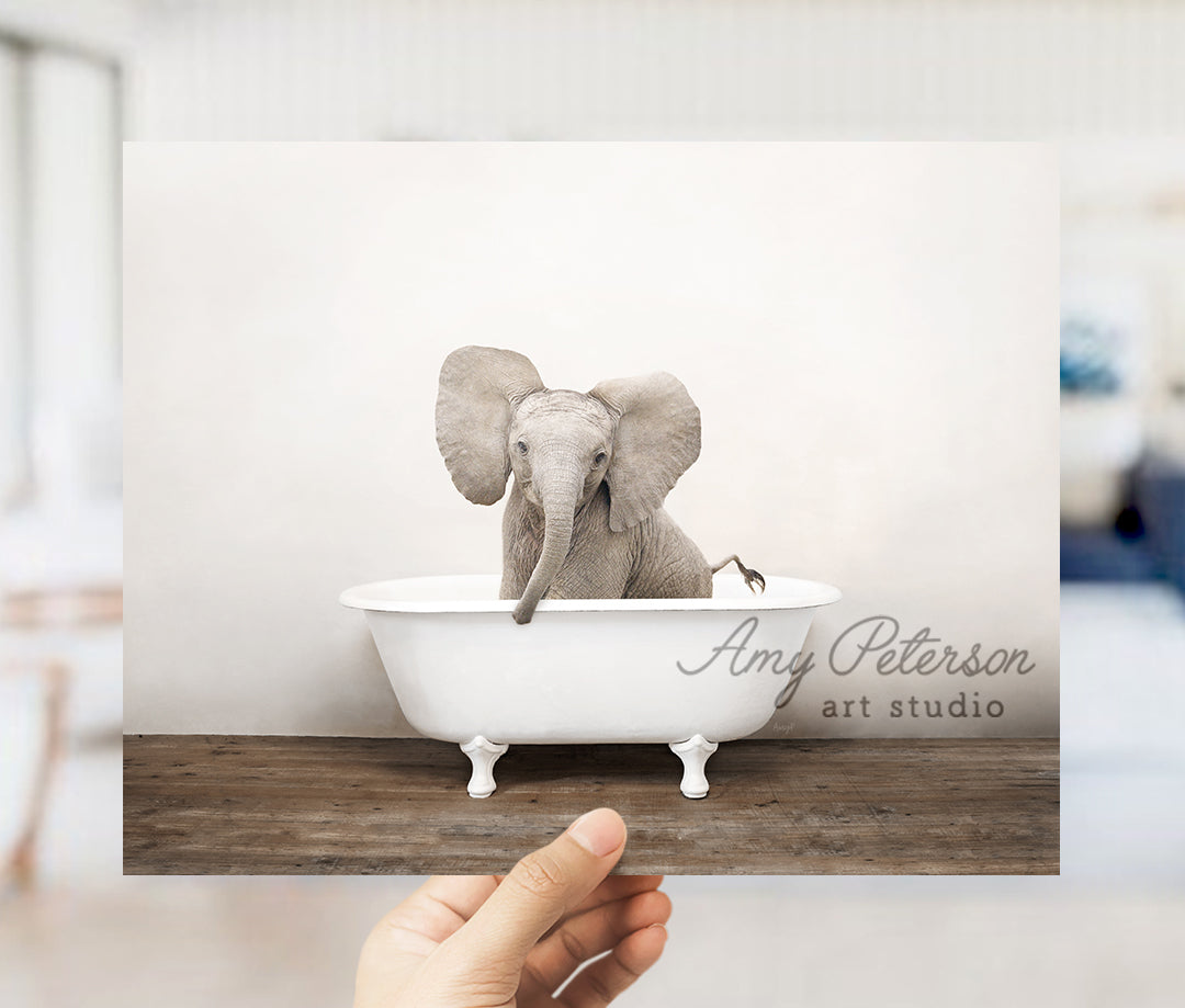 a hand holding up a card with an elephant in a bathtub