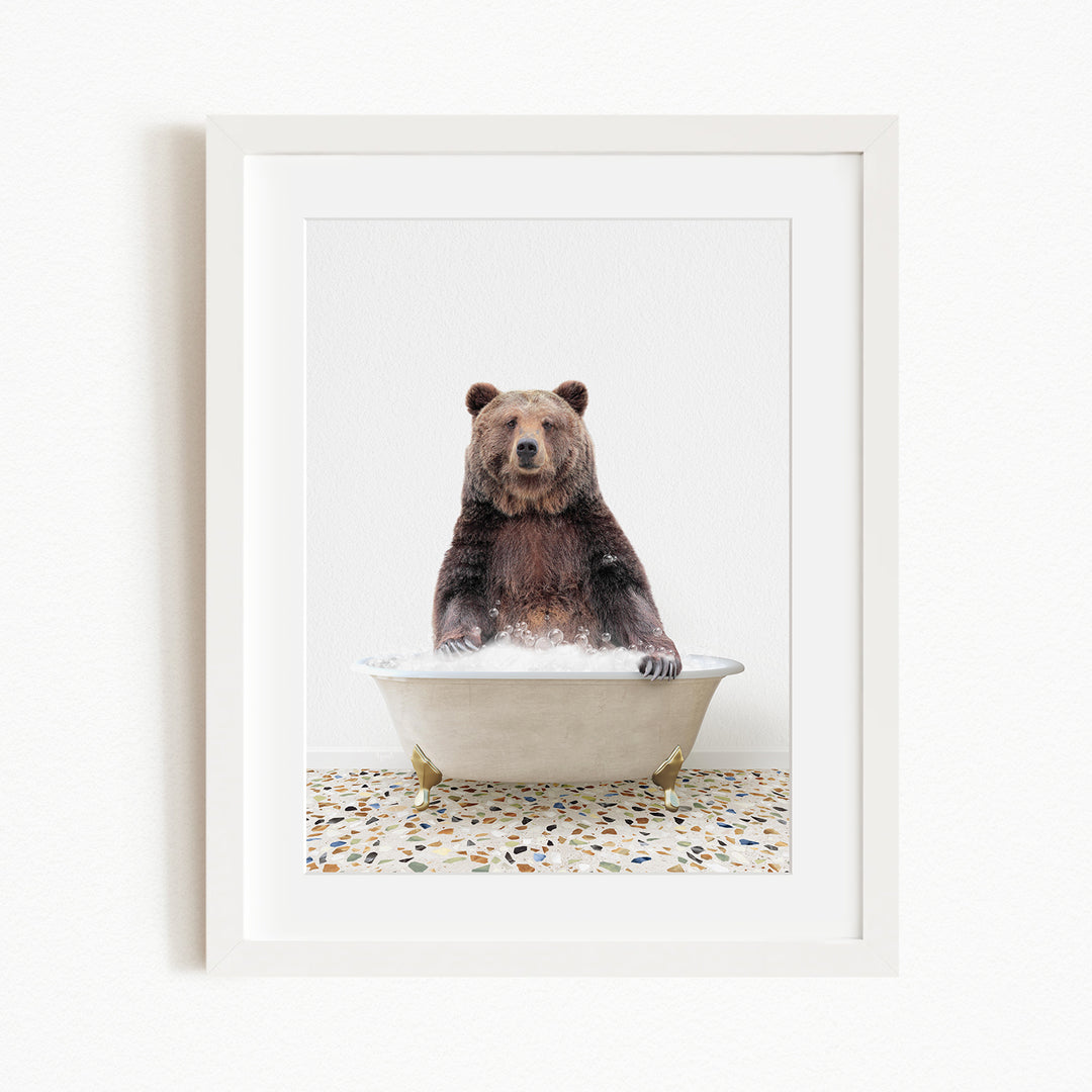 A brown bear sitting in a white bathtub filled with water, with a speckled floor beneath it.