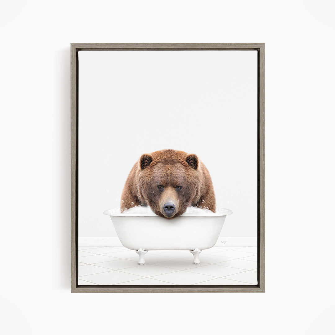 A brown bear sitting in a white bathtub filled with water, appearing to enjoy the bath.