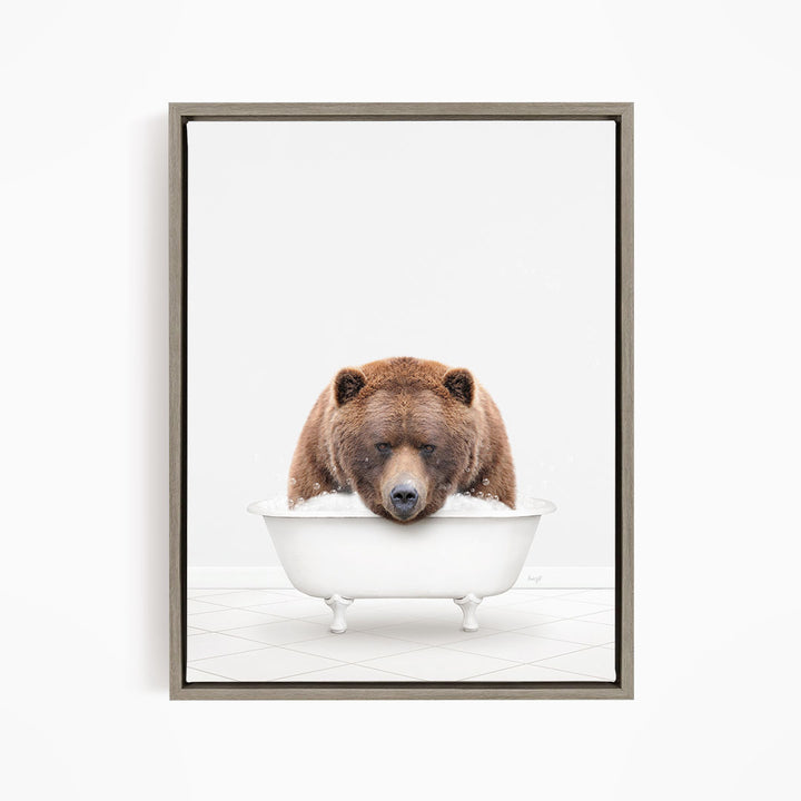 A brown bear sitting in a white bathtub filled with water, appearing to enjoy the bath.