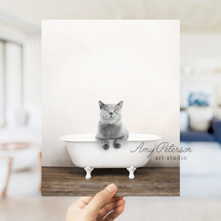 a person holding up a photo of a cat in a bathtub