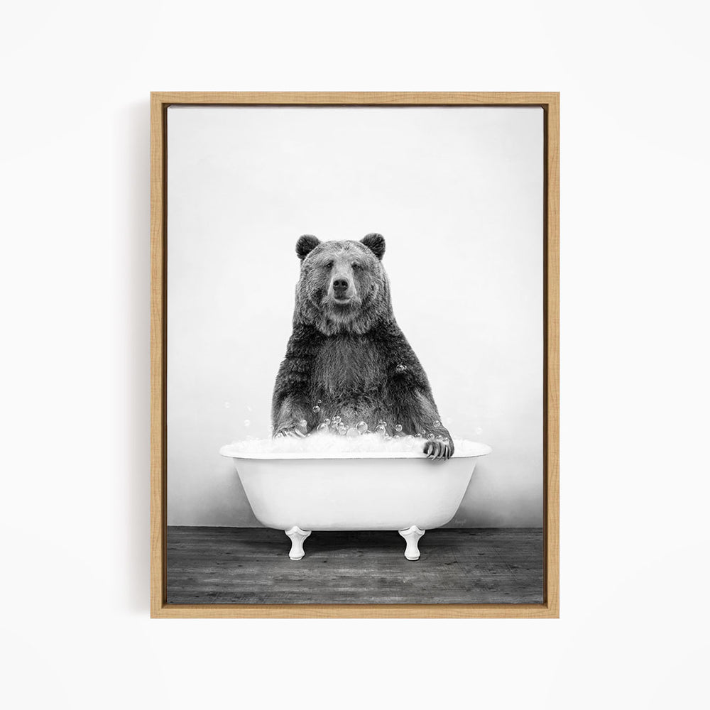 A black and white image of a bear sitting in a bathtub filled with water.