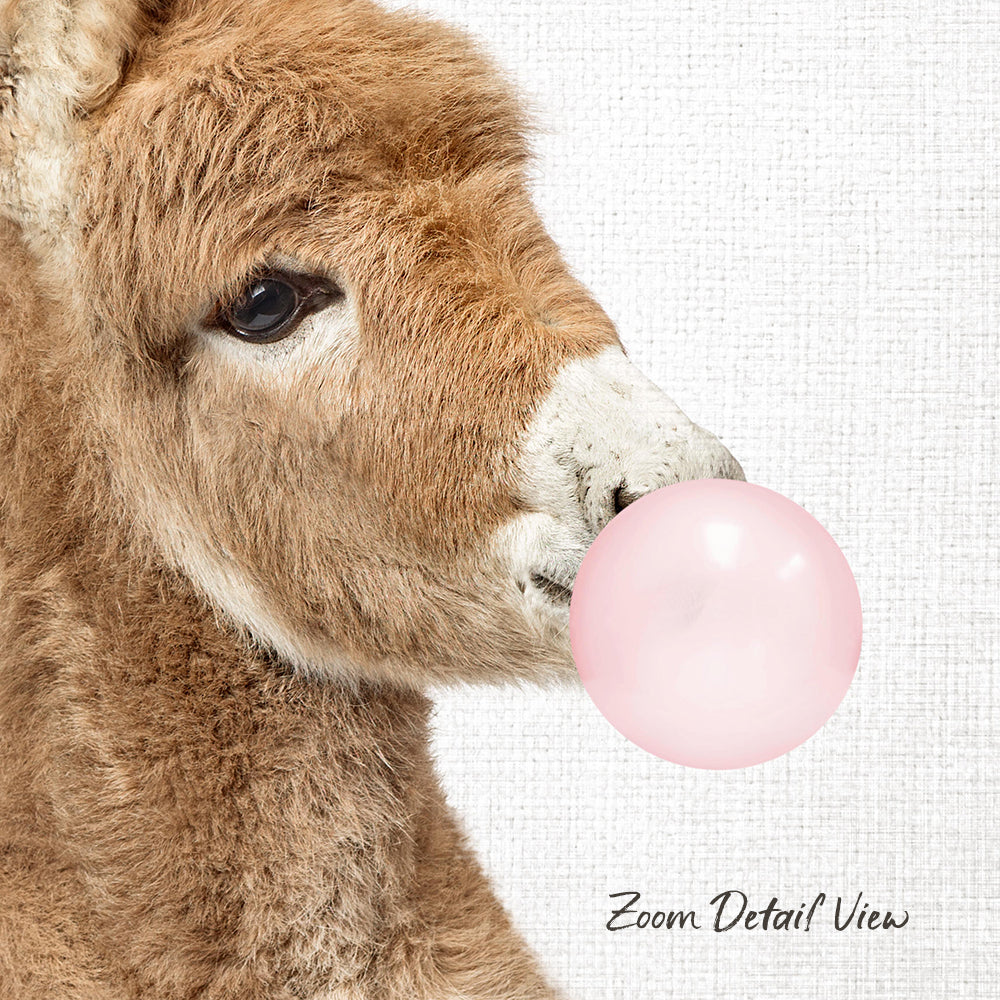 A close-up of a brown animal, possibly a donkey or a sheep, blowing a pink bubble with its mouth.