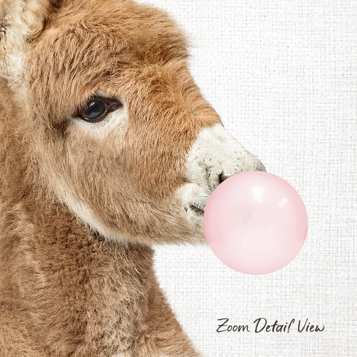 A close-up of a brown animal, possibly a donkey or a sheep, blowing a pink bubble with its mouth.