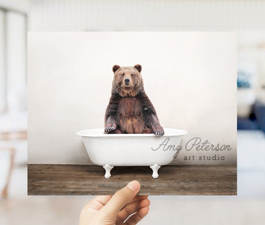 a person holding up a polaroid picture of a bear in a bathtub