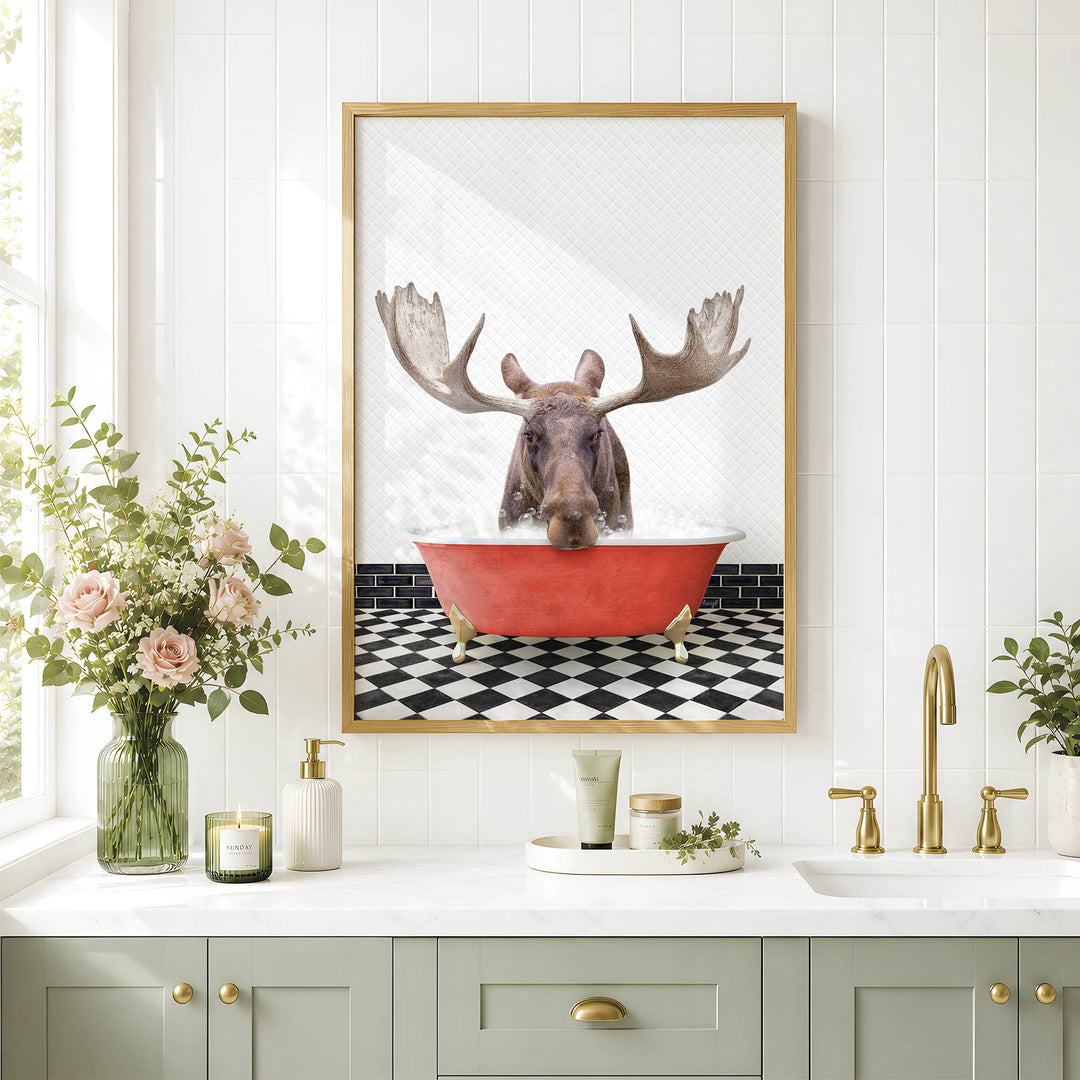 a framed picture of a moose sitting in a red bathtub, surrounded by a black and white checkered floor and a white countertop with various bathroom accessories.