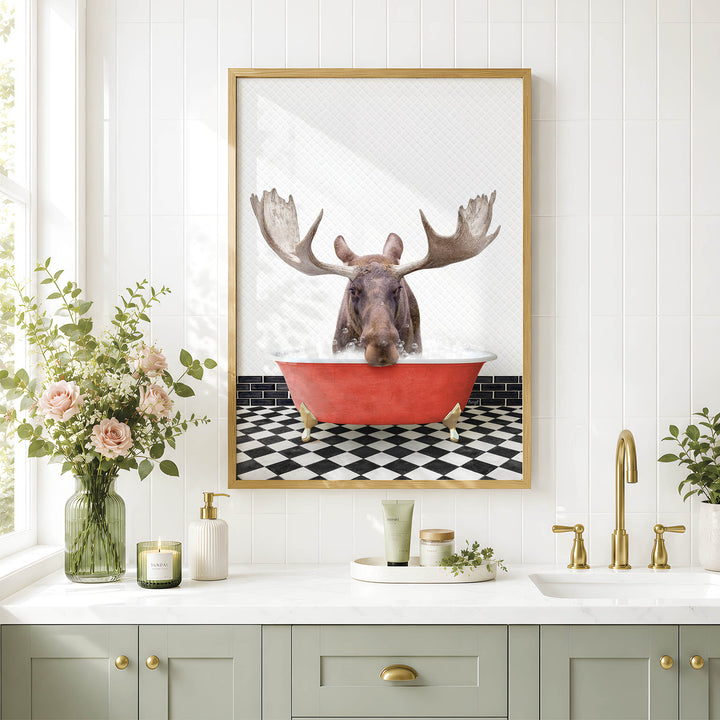 a framed picture of a moose sitting in a red bathtub, surrounded by a black and white checkered floor and a white countertop with various bathroom accessories.