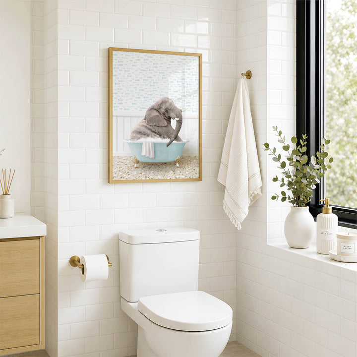A bathroom with a white toilet, a framed picture of an elephant in a bathtub, and a window with greenery on the sill.