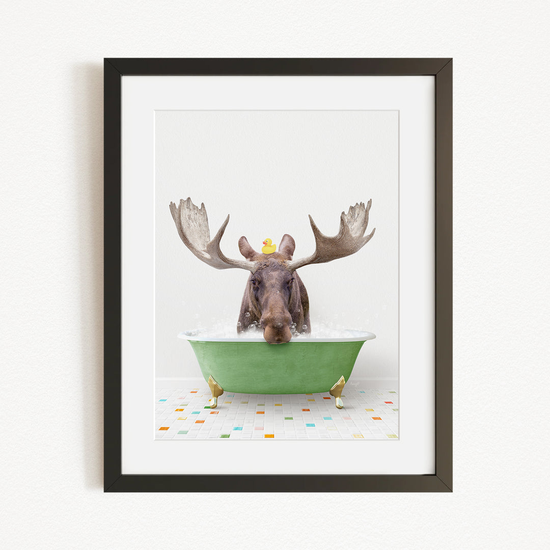 A moose with large antlers is sitting in a green bathtub, surrounded by colorful tiles on the floor.