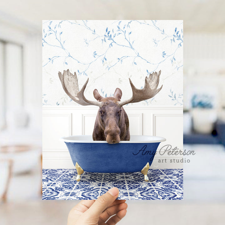 a person holding up a card with a moose head in a bathtub