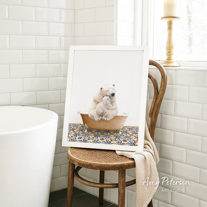 A framed image of a polar bear sitting in a bathtub, with a towel draped over the back of a wooden chair in a bathroom setting.