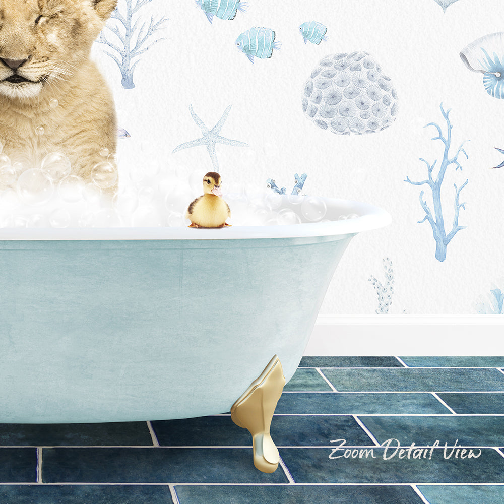 A golden lion cub is sitting in a bathtub filled with bubbles, with a small yellow duck perched on the edge of the tub. The scene is set against a wall with a blue and white marine-themed wallpaper.
