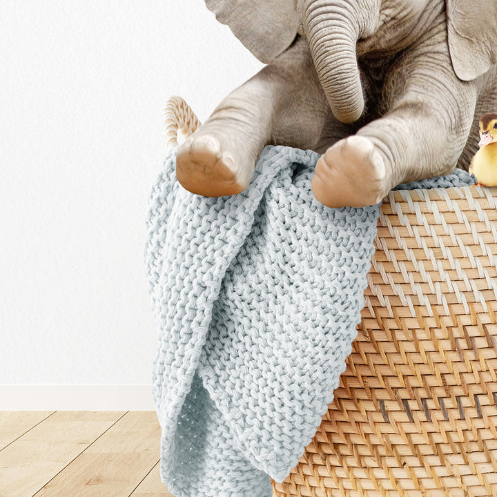 a stuffed elephant sitting on top of a basket