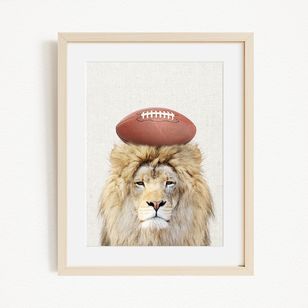 A framed image of a lion with a football on its head.