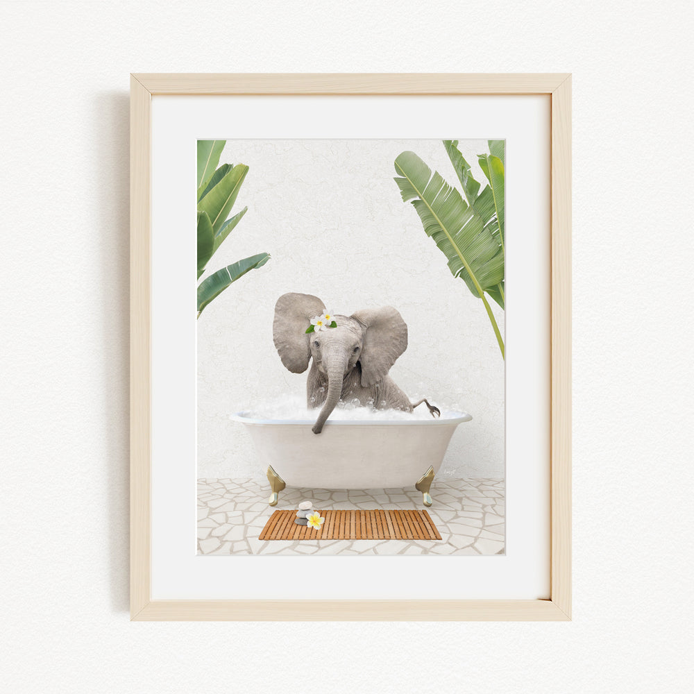 A baby elephant sitting in a bathtub filled with water, surrounded by green leaves and a wooden mat on the floor.