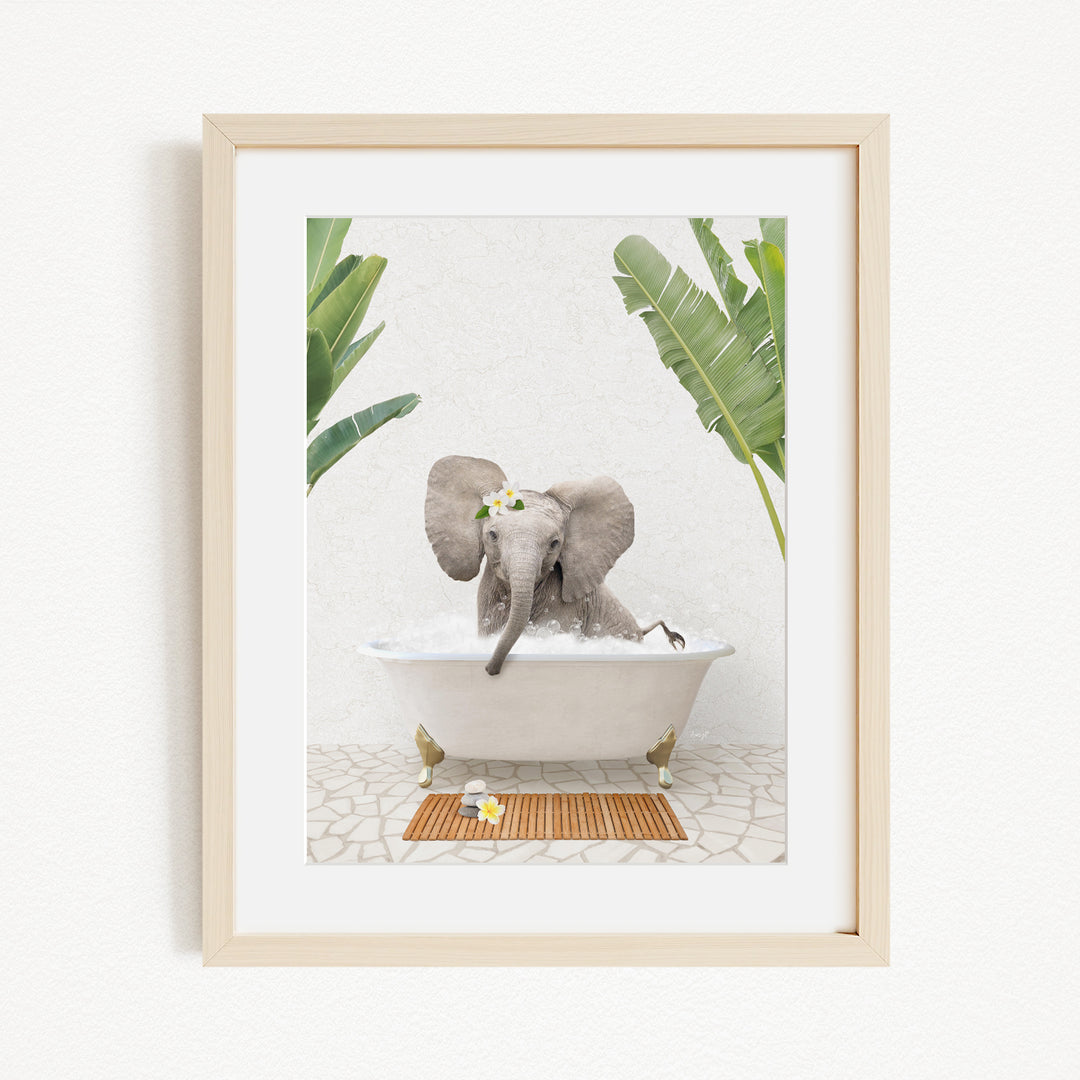 A baby elephant sitting in a bathtub filled with water, surrounded by green leaves and a wooden mat on the floor.